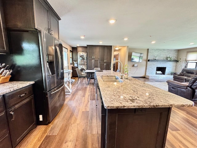 507 5th St NW, Barnesville, MN 56514 - kitchen featuring stacked washing machine and dryer, a sink, open floor plan, stainless steel refrigerator with ice dispenser, and light wood-style flooring