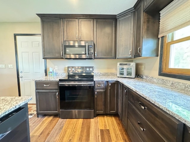 507 5th St NW, Barnesville, MN 56514 - kitchen featuring appliances with stainless steel finishes, dark brown cabinetry, light wood-type flooring, and light stone counters