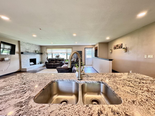507 5th St NW, Barnesville, MN 56514 - kitchen with a sink, light stone counters, recessed lighting, wood finished floors, and a fireplace