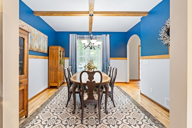 2040 Fountain Ln, Waconia, MN 55387 - dining space featuring light wood-style flooring, a chandelier, arched walkways, and beam ceiling