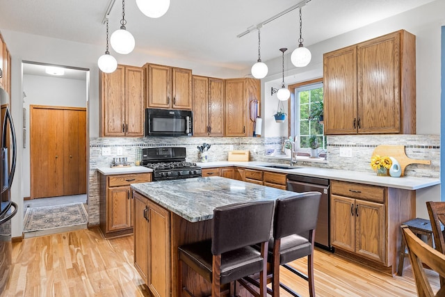 2040 Fountain Ln, Waconia, MN 55387 - kitchen with stainless steel appliances, light wood finished floors, brown cabinetry, a kitchen island, and backsplash