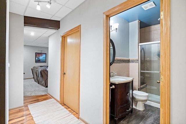 2040 Fountain Ln, Waconia, MN 55387 - ensuite bathroom with a drop ceiling, vanity, wood finished floors, a shower stall, and tile walls