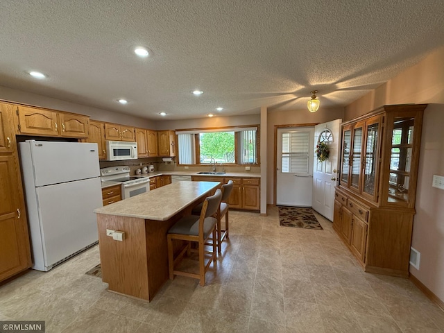 1508 Terrance Cir NE, New Prague, MN 56071 - kitchen with white appliances, a kitchen island, recessed lighting, a textured ceiling, and light countertops
