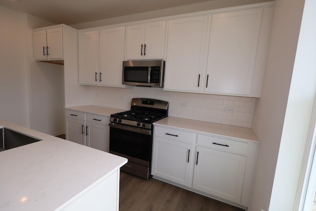 7150 Large Ave NE, Otsego, MN 55301 - kitchen featuring appliances with stainless steel finishes, white cabinets, light wood-style flooring, backsplash, and light countertops