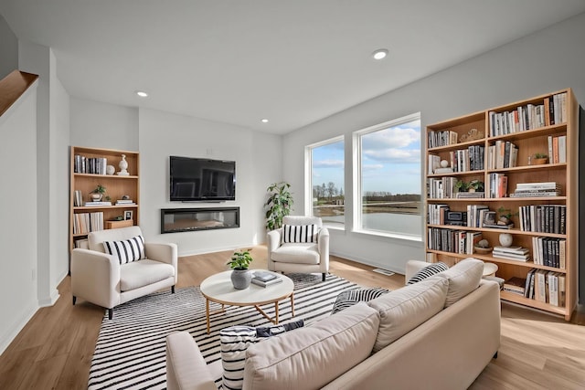 7150 Large Ave NE, Otsego, MN 55301 - living area featuring light wood-style flooring, a glass covered fireplace, recessed lighting, and baseboards