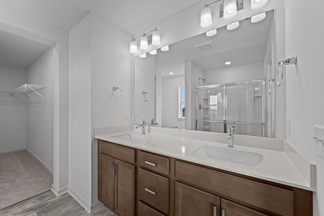 7150 Large Ave NE, Otsego, MN 55301 - bathroom featuring a shower stall, a spacious closet, double vanity, and wood finished floors