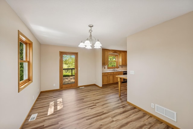 8415 Needham Ave NE, Otsego, MN 55330 - unfurnished dining area with a sink, a chandelier, light wood-type flooring, and baseboards