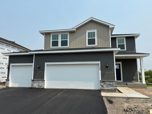 7130 Large Ave NE, Otsego, MN 55301 - view of front of property with stone siding, asphalt driveway, an attached garage, and board and batten siding