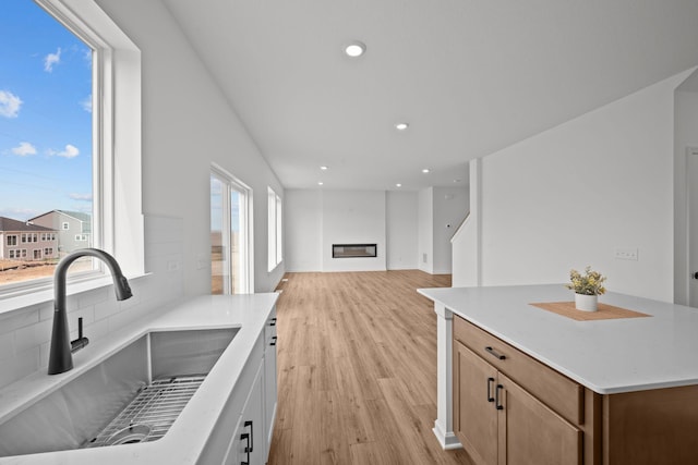 7130 Large Ave NE, Otsego, MN 55301 - kitchen featuring a sink, light wood-style flooring, tasteful backsplash, a glass covered fireplace, and recessed lighting