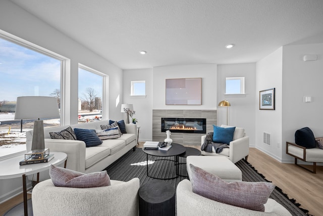 7130 Large Ave NE, Otsego, MN 55301 - living room featuring light wood-style flooring, a glass covered fireplace, baseboards, recessed lighting, and a textured ceiling
