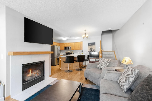 20616 Erin Way Unit 74, Farmington, MN 55024 - living area featuring light wood-type flooring, a chandelier, a tiled fireplace, a textured ceiling, and stairway