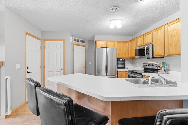 20616 Erin Way Unit 74, Farmington, MN 55024 - kitchen with stainless steel appliances, light wood-style floors, a peninsula, a sink, and light countertops
