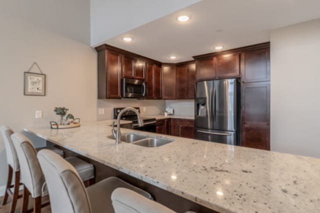 642 Haeberle Ave, New Ulm, MN 56073 - kitchen with stainless steel appliances, light stone countertops, a peninsula, a breakfast bar, and recessed lighting