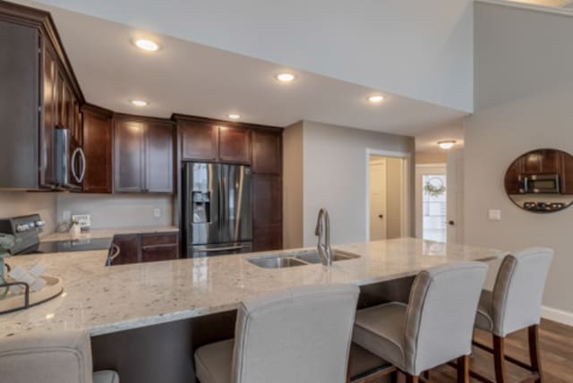 642 Haeberle Ave, New Ulm, MN 56073 - kitchen with stainless steel appliances, light stone countertops, dark brown cabinets, a peninsula, and dark wood-style flooring