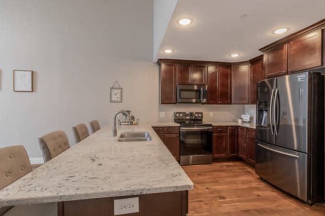 642 Haeberle Ave, New Ulm, MN 56073 - kitchen featuring appliances with stainless steel finishes, a peninsula, recessed lighting, light wood-style flooring, and light stone counters
