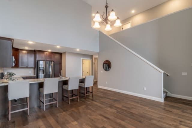642 Haeberle Ave, New Ulm, MN 56073 - kitchen with stainless steel fridge, a towering ceiling, a kitchen bar, dark brown cabinetry, and dark wood-type flooring