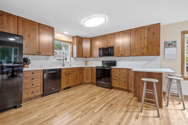 11520 120th St N, Stillwater, MN 55082 - kitchen featuring black appliances, light wood-type flooring, tasteful backsplash, brown cabinets, and a sink