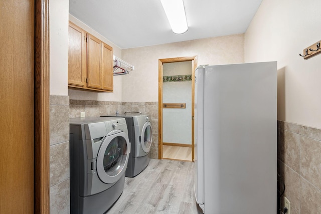11520 120th St N, Stillwater, MN 55082 - washroom with tile walls, cabinet space, washing machine and dryer, light wood-style flooring, and a wainscoted wall