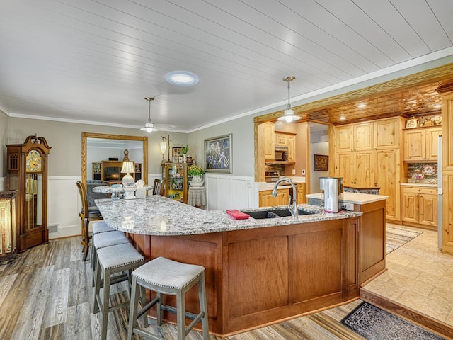 1144 Waldon Pl, Arden Hills, MN 55112 - kitchen with a sink, wainscoting, stainless steel microwave, light stone countertops, and a kitchen breakfast bar