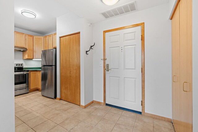 560 2nd St Unit 408, Minneapolis, MN 55401 - kitchen featuring appliances with stainless steel finishes, light brown cabinets, baseboards, under cabinet range hood, and light tile patterned floors