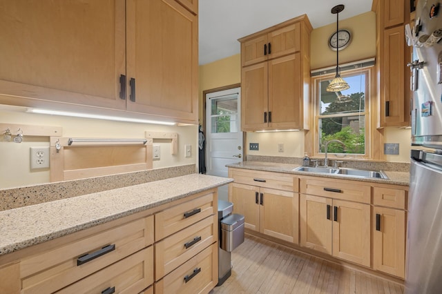 1441 Simpson St, Saint Paul, MN 55108 - kitchen with light brown cabinetry, pendant lighting, light wood-style floors, light stone counters, and fridge