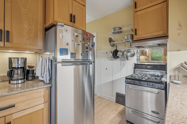 1441 Simpson St, Saint Paul, MN 55108 - kitchen with appliances with stainless steel finishes, light wood finished floors, light stone counters, and wall chimney range hood