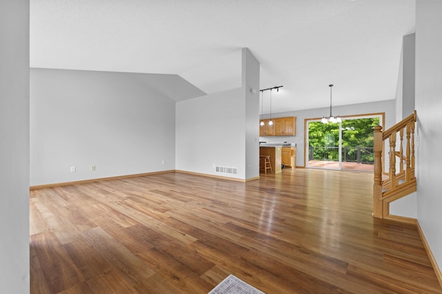 18358 Jenkins St NE, East Bethel, MN 55011 - unfurnished living room with lofted ceiling, light wood finished floors, a chandelier, baseboards, and stairway