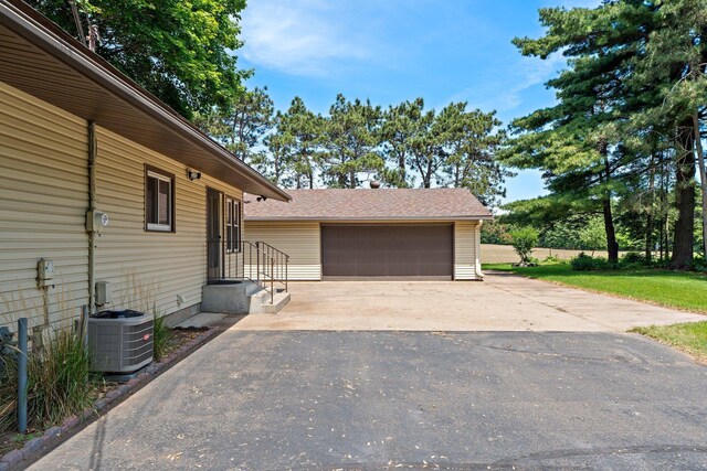 8170 113th St S, Cottage Grove, MN 55016 - view of home's exterior featuring central AC, an outdoor structure, a detached garage, and a shingled roof