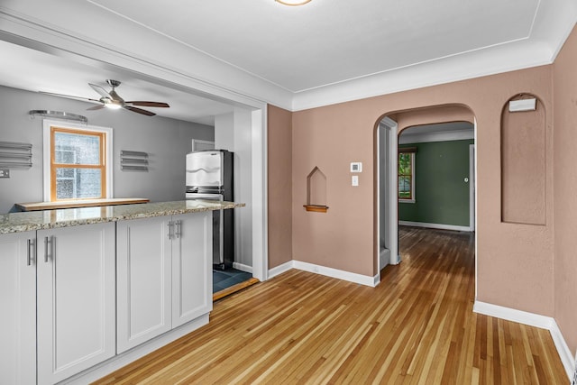 5749 Pleasant Ave S, Minneapolis, MN 55419 - kitchen with freestanding refrigerator, arched walkways, light wood-type flooring, baseboards, and white cabinets
