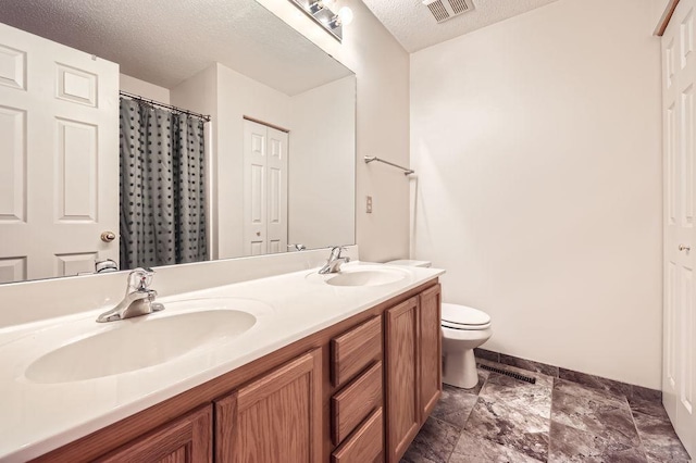 1059 Providence Dr, Shakopee, MN 55379 - bathroom with double vanity, a textured ceiling, baseboards, toilet, and stone finish floors