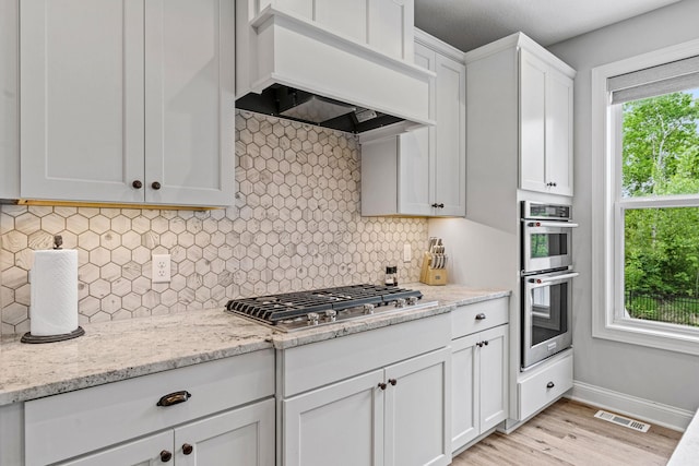 7137 61st St S, Cottage Grove, MN 55016 - kitchen featuring custom exhaust hood, stainless steel appliances, white cabinetry, light wood-type flooring, and baseboards