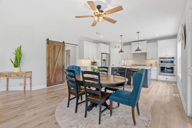 7137 61st St S, Cottage Grove, MN 55016 - dining room featuring a barn door, light wood-style floors, a ceiling fan, recessed lighting, and baseboards