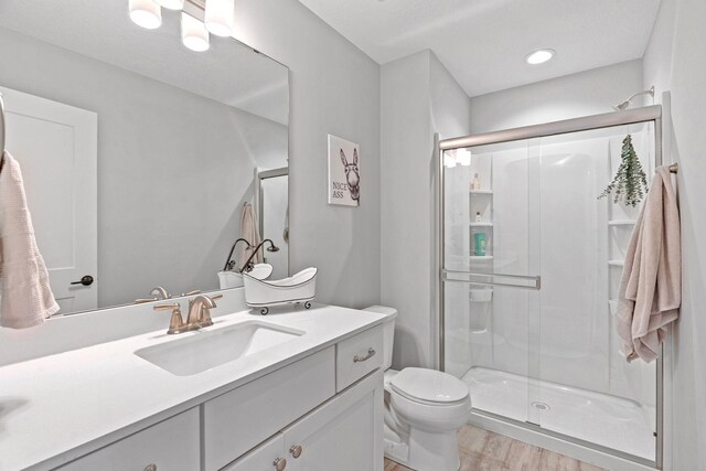 7137 61st St S, Cottage Grove, MN 55016 - bathroom featuring vanity, a stall shower, toilet, wood finished floors, and recessed lighting