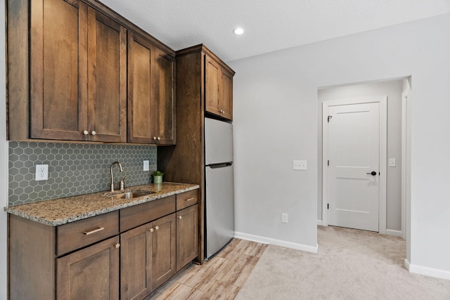 7137 61st St S, Cottage Grove, MN 55016 - kitchen with a sink, freestanding refrigerator, light stone counters, baseboards, and tasteful backsplash