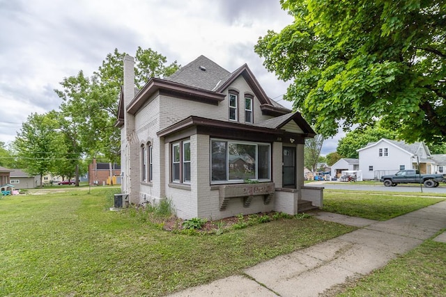202 Adams St, Arlington, MN 55307 - view of front of house with brick siding, a front lawn, a chimney, central air condition unit, and a shingled roof