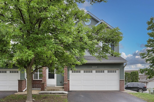 3007 Cutters Grove Ave, Anoka, MN 55303 - obstructed view of property featuring asphalt driveway, brick siding, and a garage