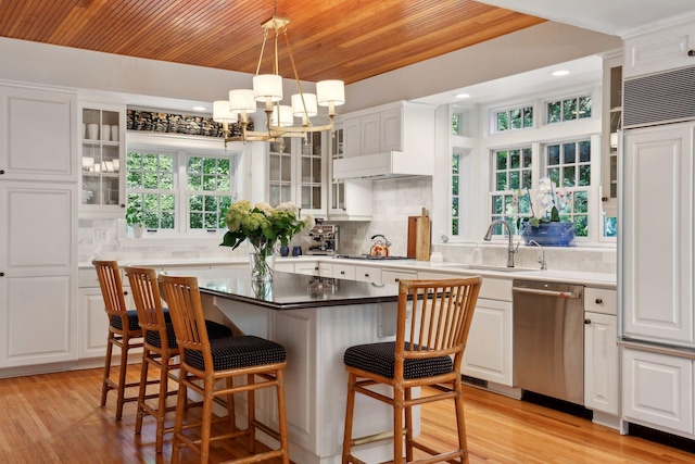 14 Forest Dale Rd, Minneapolis, MN 55410 - kitchen featuring stainless steel dishwasher, a kitchen breakfast bar, white cabinetry, tasteful backsplash, and a chandelier