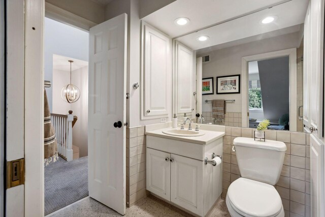 14 Forest Dale Rd, Minneapolis, MN 55410 - bathroom featuring vanity, tile walls, speckle patterned floor, recessed lighting, and toilet