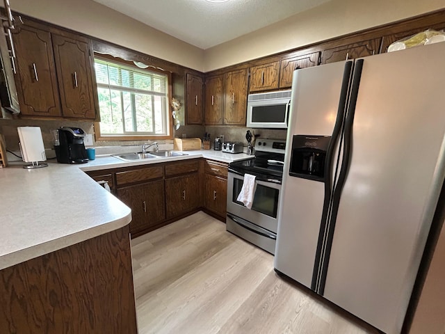 3476 116th Ln NW, Coon Rapids, MN 55433 - kitchen featuring appliances with stainless steel finishes, a sink, light wood-style floors, decorative backsplash, and light countertops