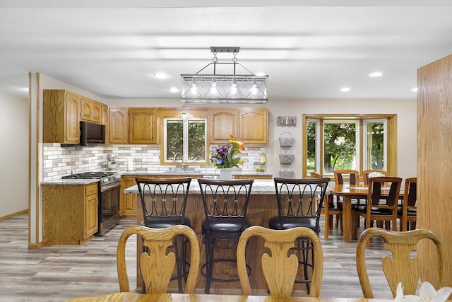 843 Northdale Blvd NW, Coon Rapids, MN 55448 - kitchen with gas range, light wood-style flooring, decorative backsplash, a sink, and a center island