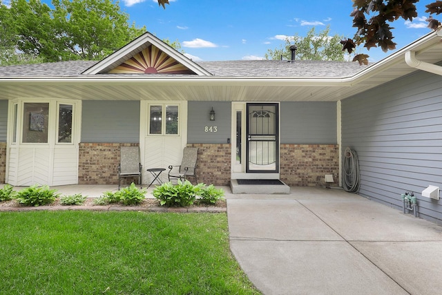 843 Northdale Blvd NW, Coon Rapids, MN 55448 - entrance to property featuring brick siding, a porch, a shingled roof, and a lawn
