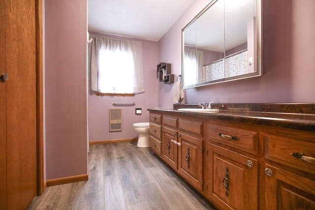 208 Concord St, West Concord, MN 55985 - full bath with vanity, heating unit, baseboards, toilet, and wood finished floors