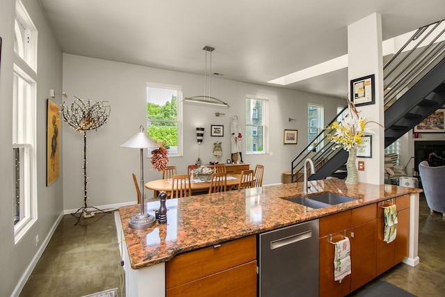 512 Laurel Ave Unit 1, Saint Paul, MN 55102 - kitchen featuring stainless steel dishwasher, brown cabinets, light stone countertops, an island with sink, and pendant lighting