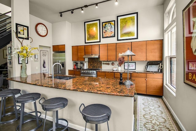 512 Laurel Ave Unit 1, Saint Paul, MN 55102 - kitchen with brown cabinets, under cabinet range hood, stainless steel appliances, and a breakfast bar area