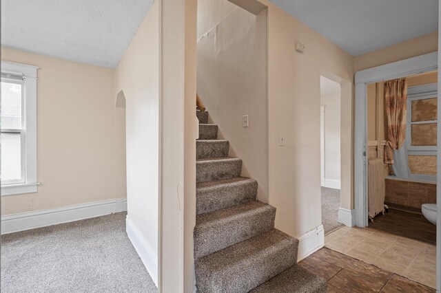 3328 5th Ave S, Minneapolis, MN 55408 - stairs featuring arched walkways, baseboards, and radiator heating unit