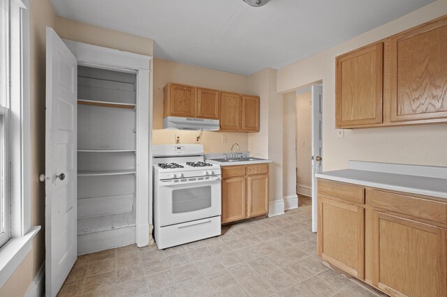 3328 5th Ave S, Minneapolis, MN 55408 - kitchen featuring white gas range oven, under cabinet range hood, a sink, and light countertops