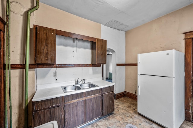 3328 5th Ave S, Minneapolis, MN 55408 - kitchen featuring freestanding refrigerator, a sink, light countertops, arched walkways, and dark brown cabinetry