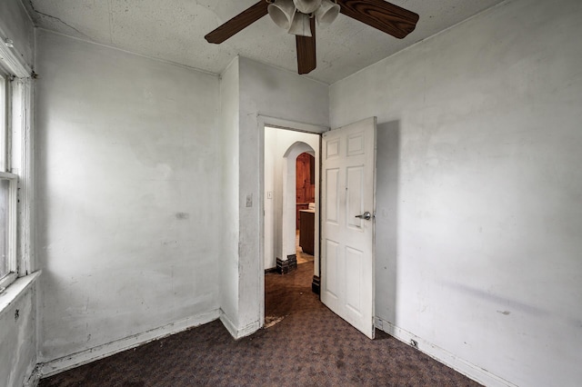 3328 5th Ave S, Minneapolis, MN 55408 - empty room with a ceiling fan, arched walkways, dark carpet, and baseboards