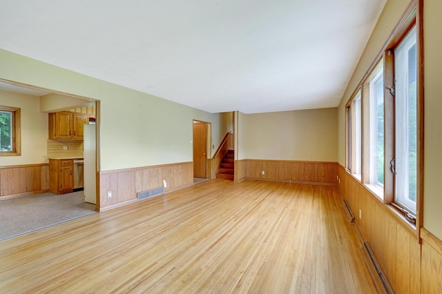 11418 Friar Ln, Minnetonka, MN 55305 - empty room featuring a wainscoted wall, light wood-style flooring, wood walls, baseboard heating, and stairs