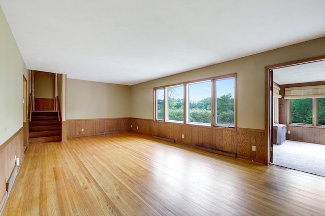 11418 Friar Ln, Minnetonka, MN 55305 - unfurnished room featuring a wainscoted wall, light wood-type flooring, wooden walls, a baseboard heating unit, and stairs